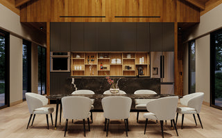 Modern open kitchen interior design for a mountain cabin featuring a black marble island with open shelving for pantry items, along with a large fridge and oven. The dining area includes a marble table surrounded by upholstered white linen chairs.