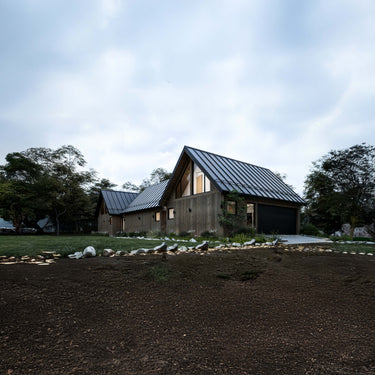 Wooden cabin with metal roof surrounded by trees on a cloudy day