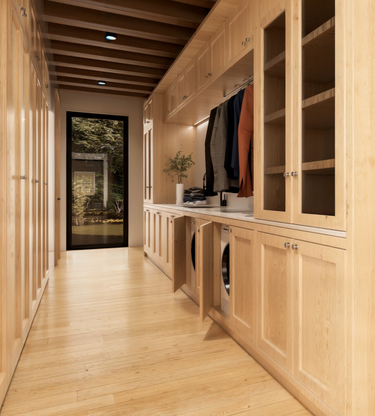 A minimalist interior hallway in Moose Meadow’s cabin, connecting the laundry closet with a glass door leading to the outdoors. The hallway transitions through a breezeway that links the common areas, while the wood cabinets and beamed ceiling create a warm and comforting interior design.
