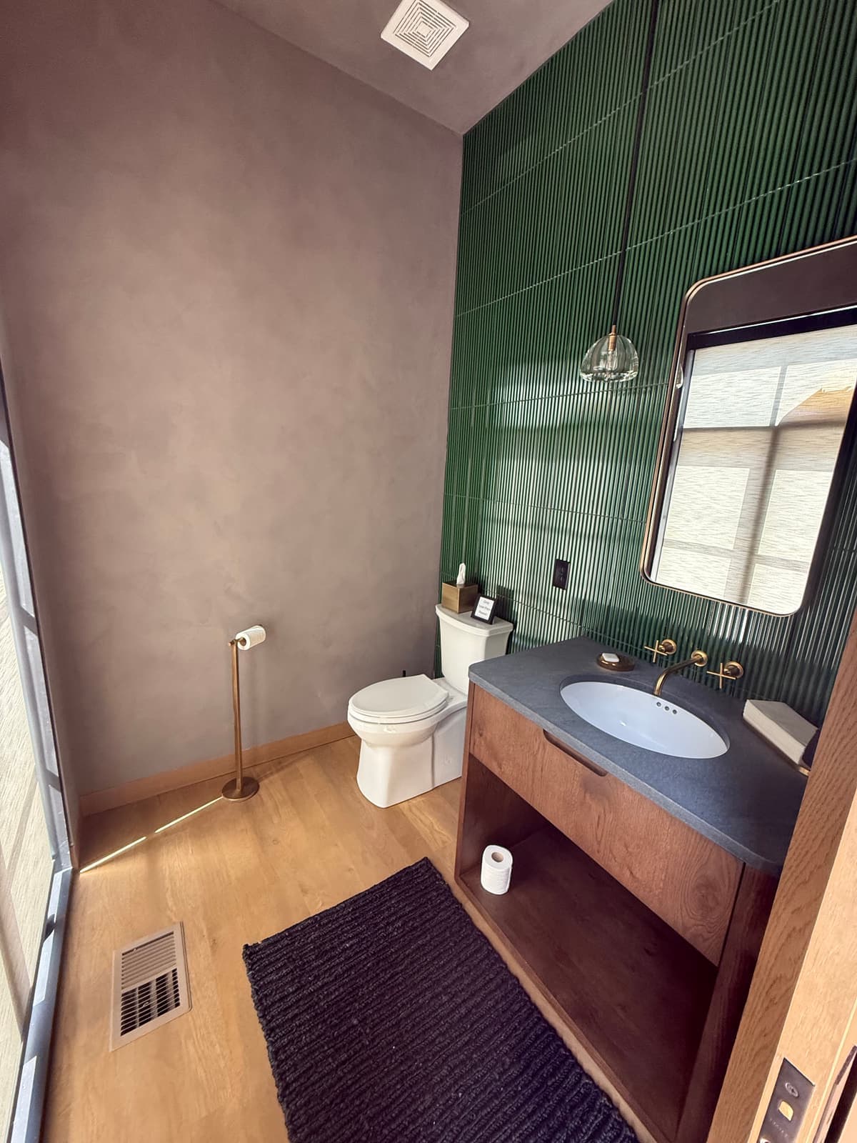 A bathroom with green walls and a wood vanity.