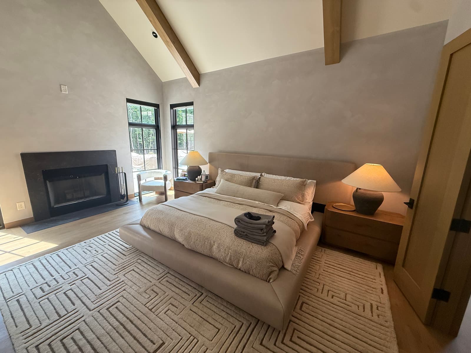 A fireplace wall with a sofa and a tall window.