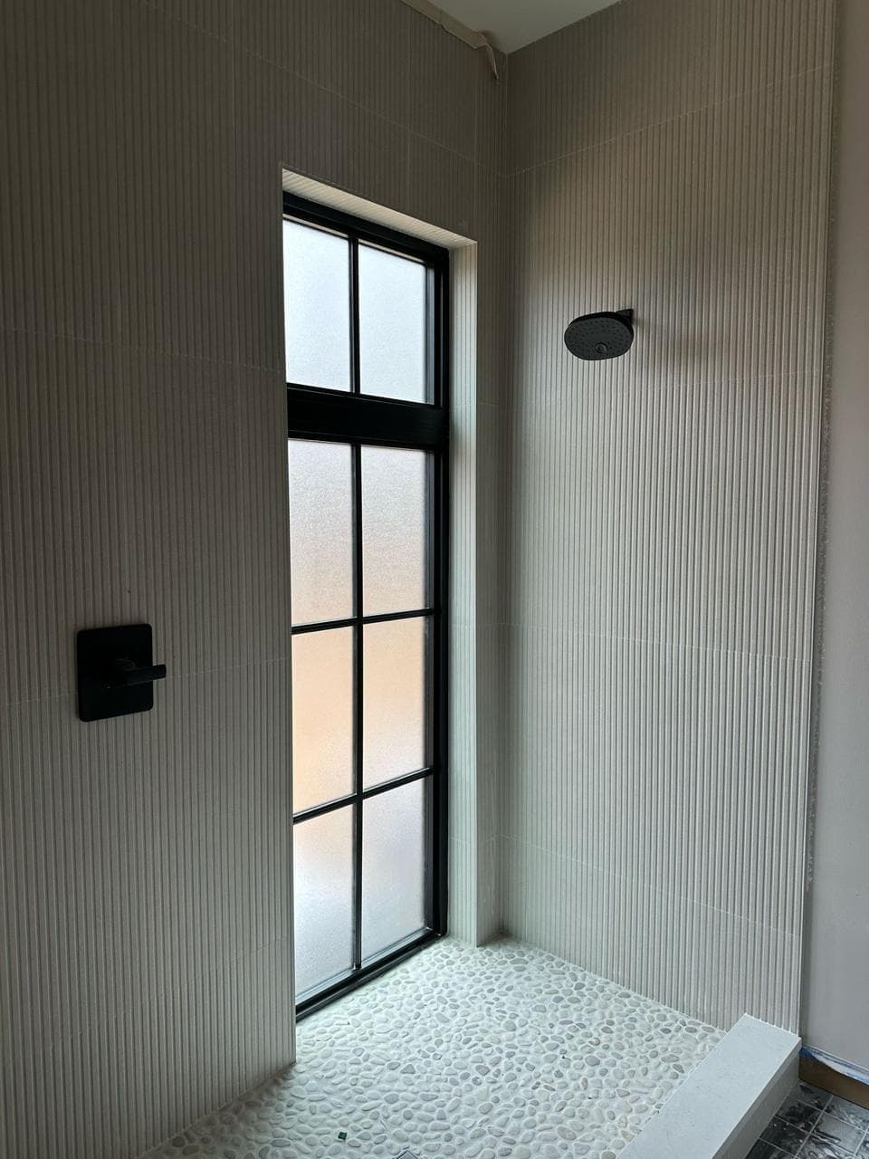 A room in drywall with a tall black window.