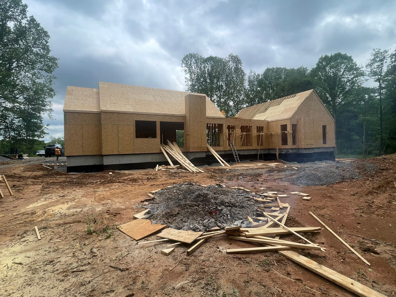 A framed timber volume on bare red soil, pines behind.