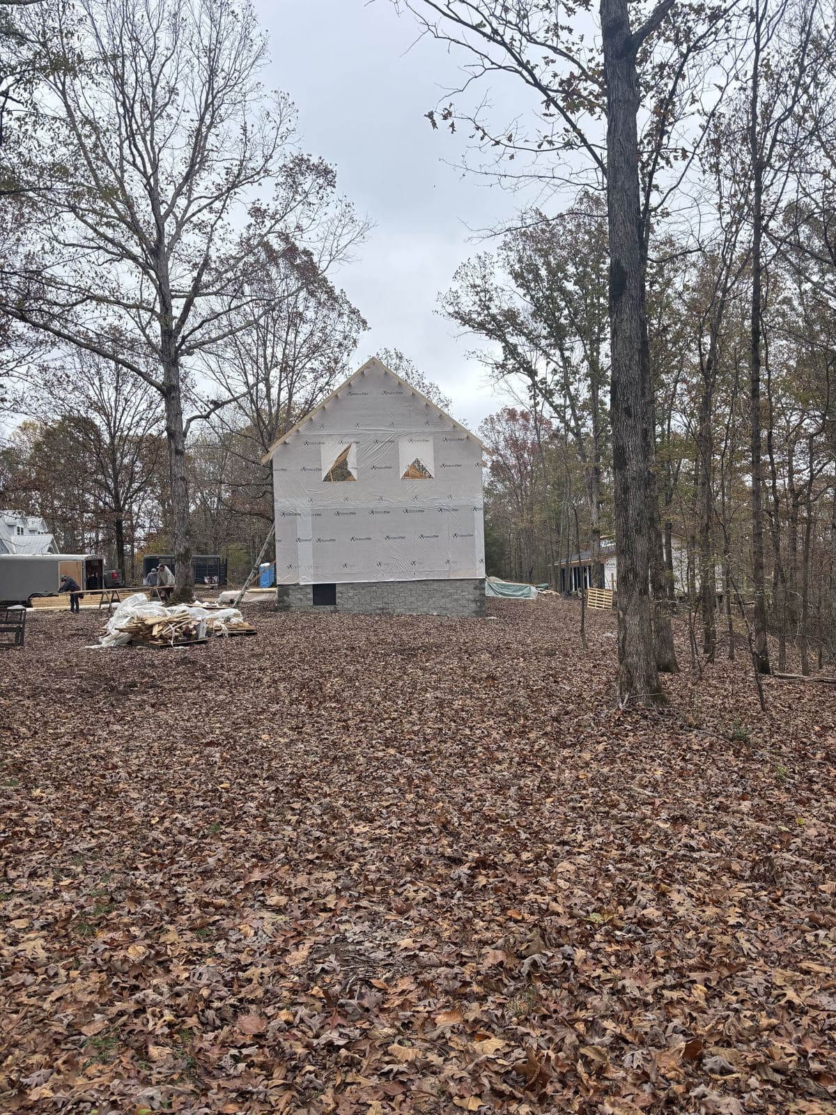 The gable wrapped, standing among the oaks, leaves on the ground.