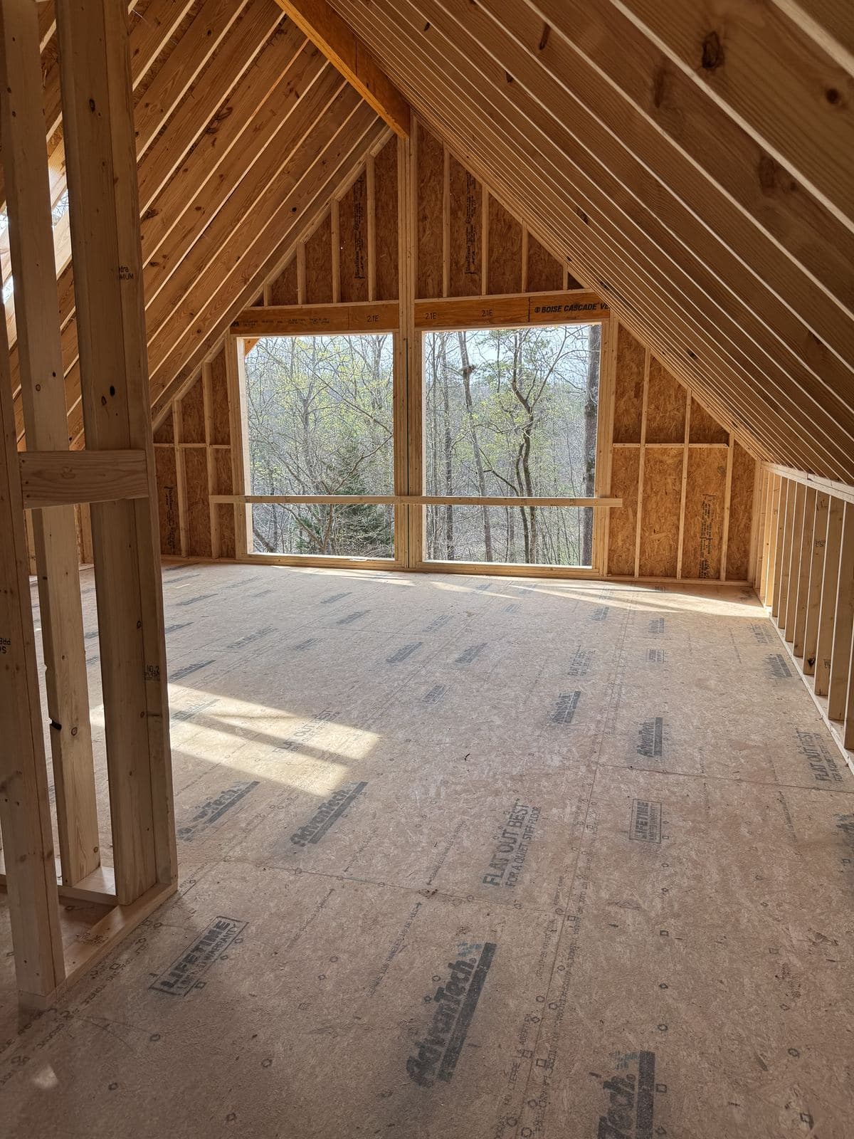 The gable room framed, the window wall open to the trees.