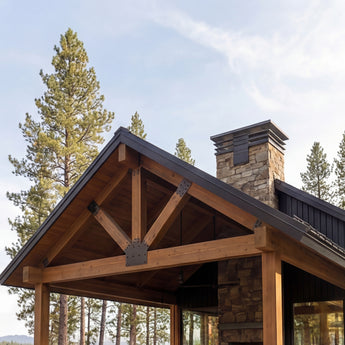 Bear's Lair, a modern wooden home in a forest setting with a stone chimney and trees in the background. A residence with an open-concept layout, vaulted ceilings, and expansive floor-to-ceiling windows. 