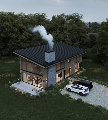 Aerial view of a modern cabin nestled in the forest, featuring a sloped black metal roof, central stone chimney with smoke, and wood-clad exterior with large vertical windows. A gravel driveway with two parked cars and a cozy patio with a firepit enhance the natural setting.