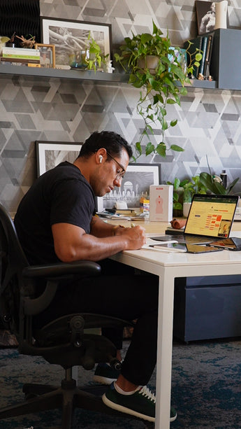 Josh is taking a discovery meeting with one of our custom home clients at his desk with art and plants around him. 