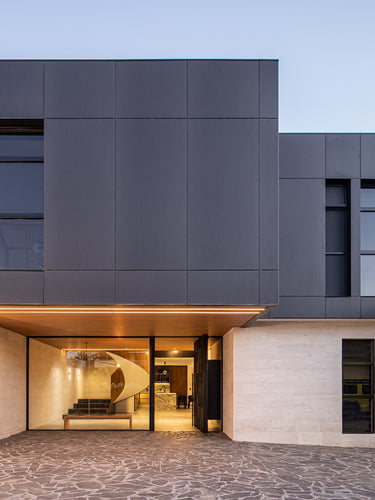 Modern house exterior with dark gray facade and glass doors.