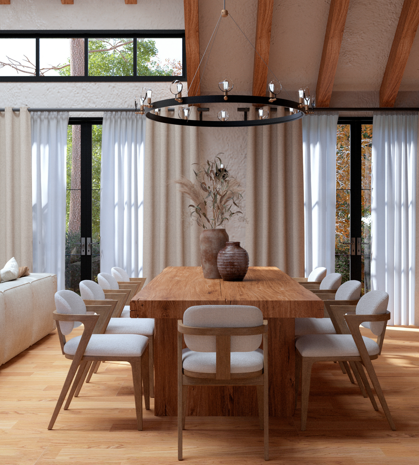 A cozy dining area with a large wooden table surrounded by eight upholstered chairs with wooden frames. The room features floor-to-ceiling beige curtains, large windows with black frames letting in natural light, exposed wooden ceiling beams, and a black circular chandelier with glass light fixtures. A neutral-toned sofa is partially visible in the background, along with greenery outside the windows.