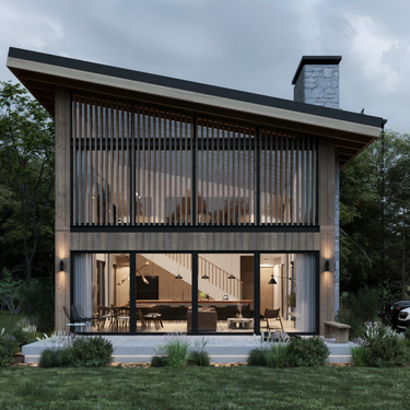 Modern A-frame-inspired two-story cabin with vertical wood slats and large glass windows, set in a forested area. The interior features a visible staircase, pendant lighting, and cozy wooden furnishings. The exterior has a sleek sloped roof, stone chimney, and landscaped garden with patio seating.